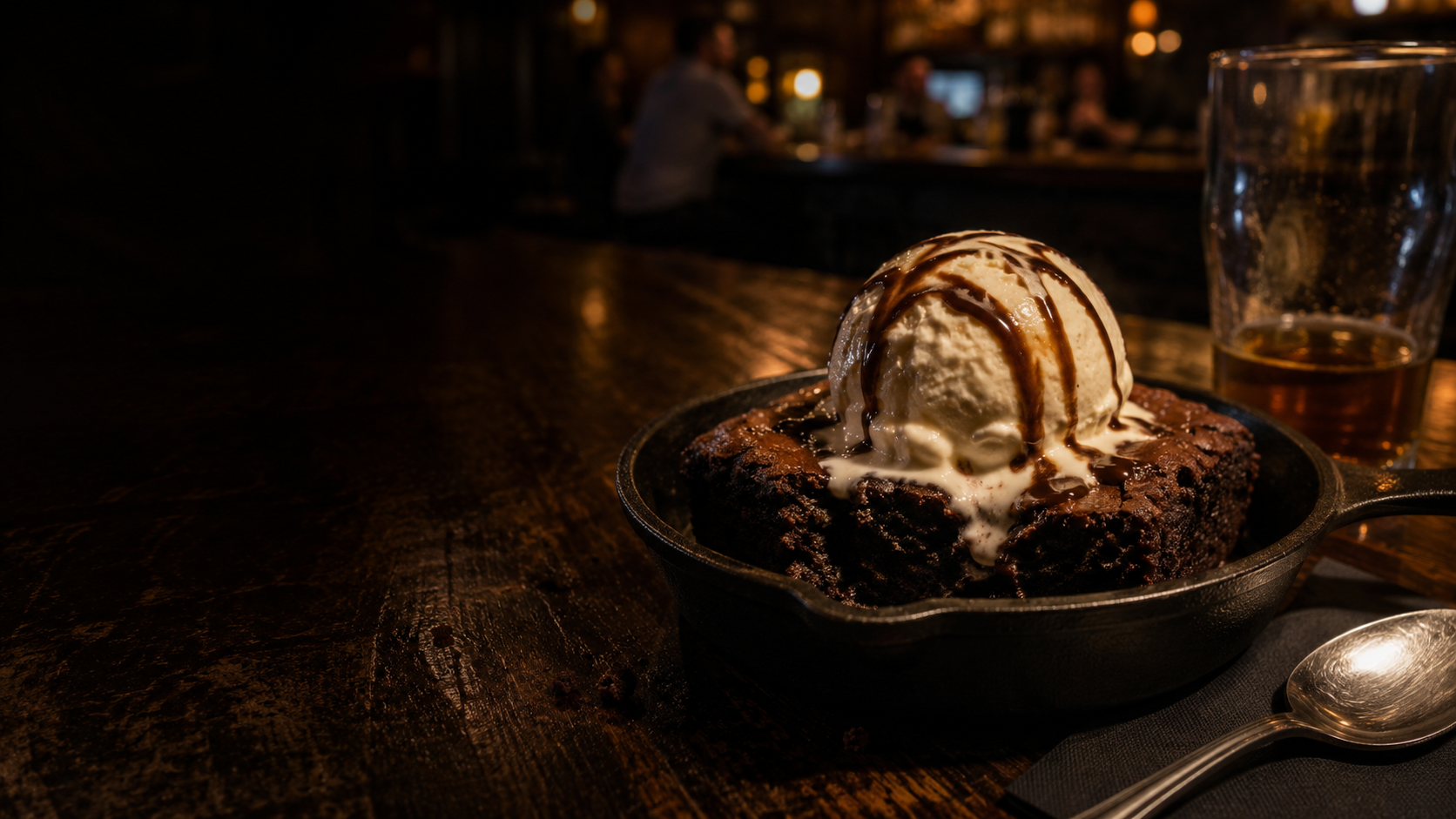 Warm chocolate brownie with melting vanilla ice cream served in a cast-iron skillet